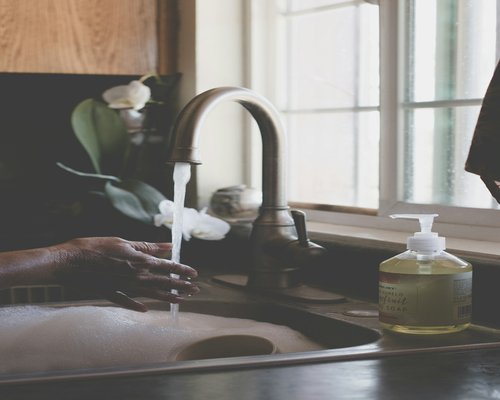 Person washing hands thoroughly in a bright kitchen sink